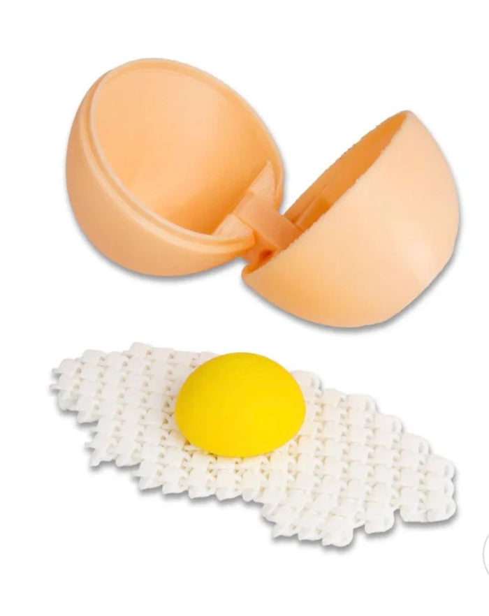 Open peach plastic egg shell beside a 3D printed fried egg with a yellow yolk and a layered white textured base.