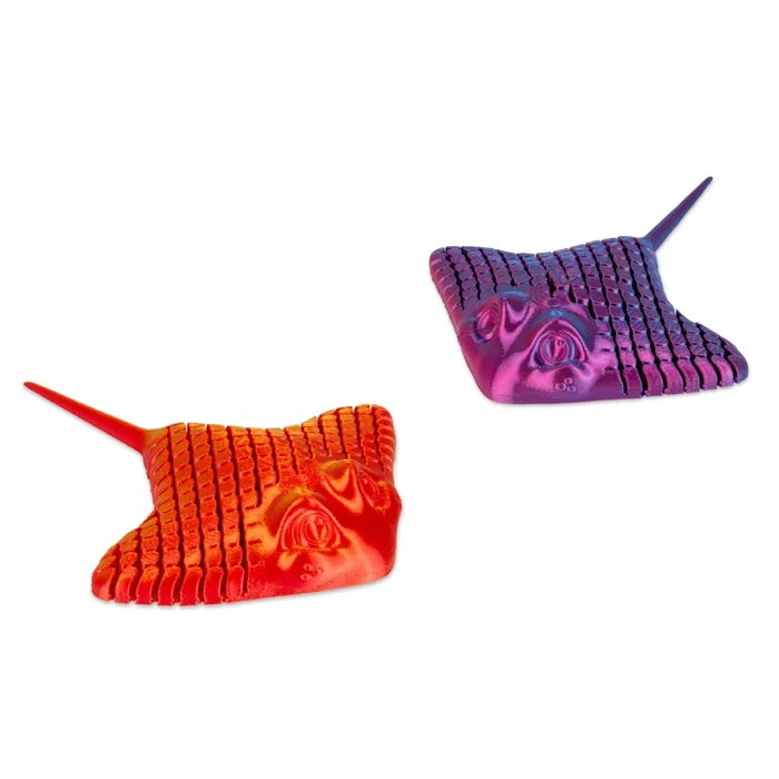Two 3D-printed articulated stingray toys in red-orange and purple-blue gradients with segmented, ridged textures.