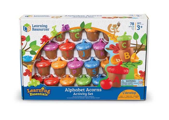 Boxed toy set of colorful plastic acorns with lettered bases and vibrant caps shown through a clear window display.