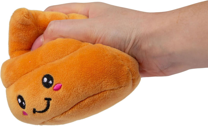 Hand squeezing an orange plush poop toy with a cute embroidered smiling face and pink cheeks.