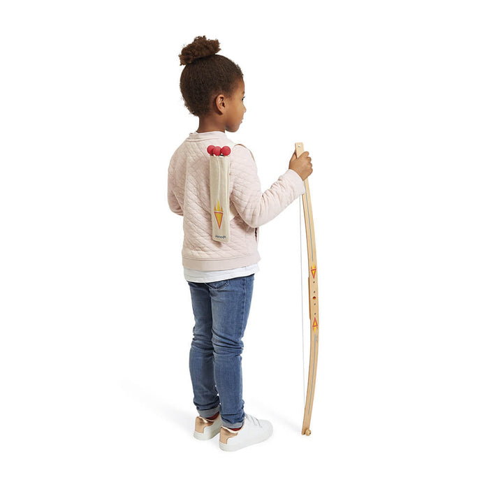 Wooden toy bow with orange patterns held by a child wearing a fabric quiver with three red-tipped arrows on her back.