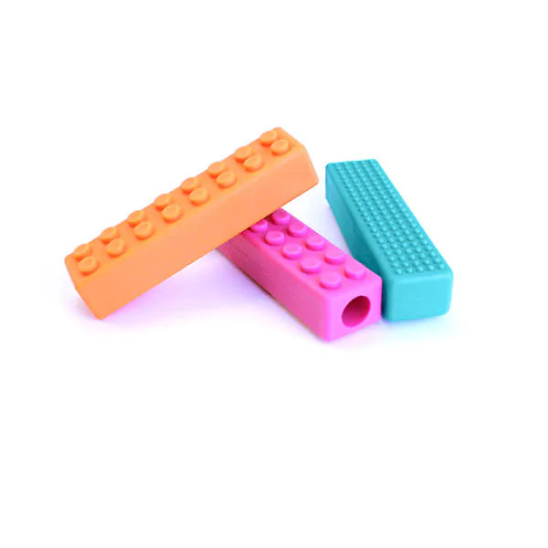Orange, pink, and teal rectangular silicone pencil toppers with building block-style studs and sensory textures.