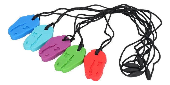 Five dinosaur head silicone chew pendants in blue, light blue, purple, green, and red on thin black break-away cords.