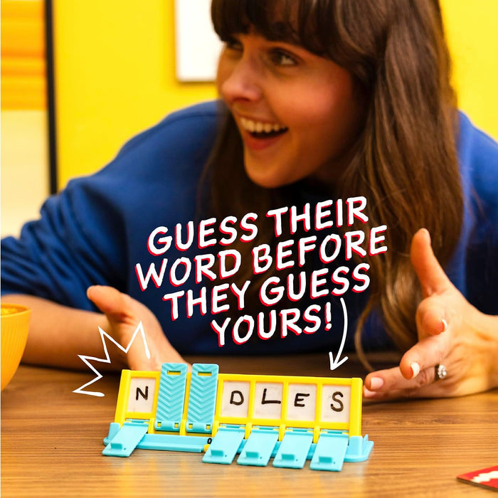 A woman smiles behind a teal and yellow word game stand with flip tiles spelling N _ _ DLES.