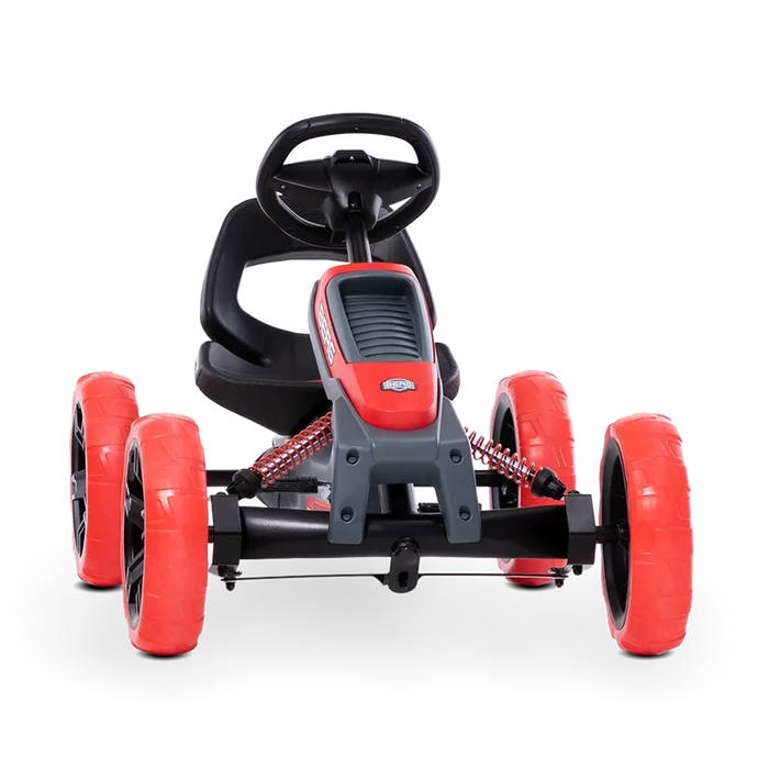 Red and black pedal go-kart with chunky red wheels, black steering wheel, and visible red front suspension springs.