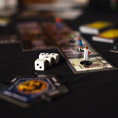 Four white dice and a painted character miniature in a white lab coat standing on room tiles for a board game.
