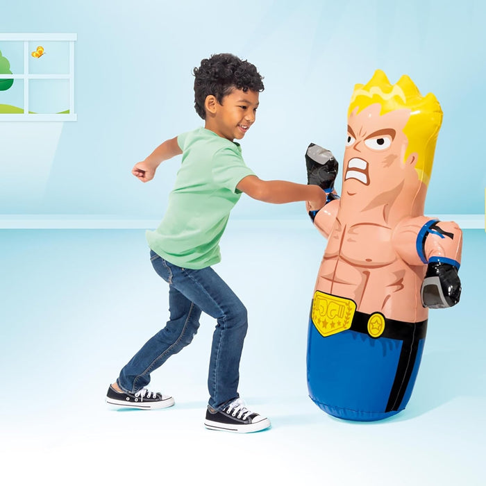 Child punches a muscular cartoon boxer inflatable bop bag with blond hair and blue trunks in a blue playroom.