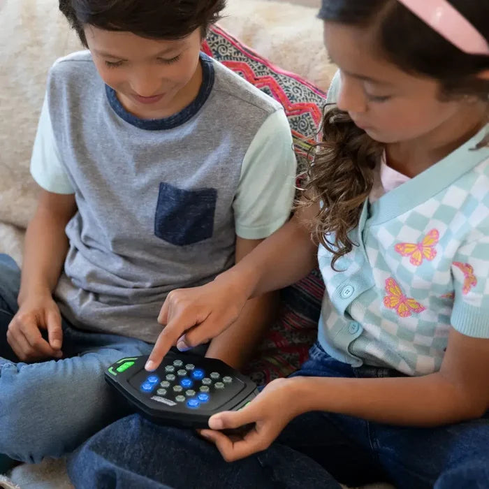 Two children play with a black hexagonal handheld game featuring circular buttons glowing blue and green.