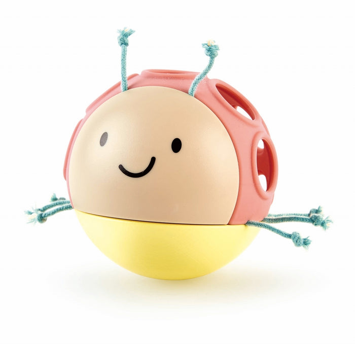 Spherical bug toy with a beige smiley face, pink shell with holes, yellow base, and knotted teal rope legs and antennae.