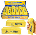 Yellow rectangular squishies labeled as salted butter sticks in a display box and being squeezed by a hand.