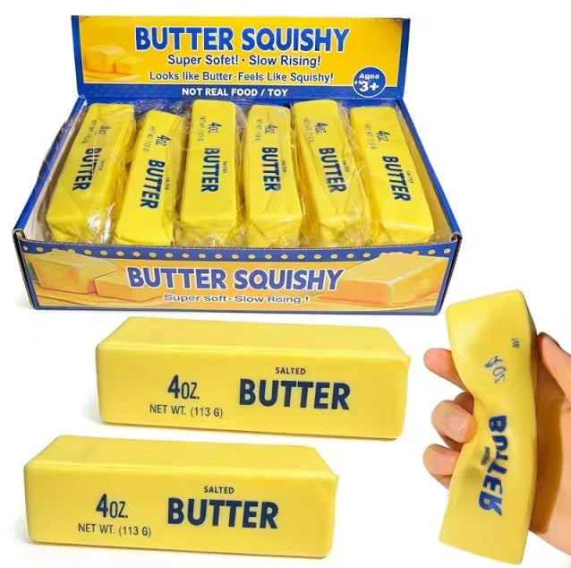 Yellow rectangular squishies labeled as salted butter sticks in a display box and being squeezed by a hand.