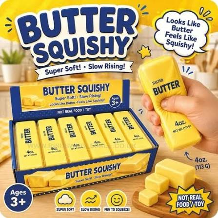 Hand squeezing a yellow foam butter stick toy next to a blue display box filled with more butter-shaped squishies.
