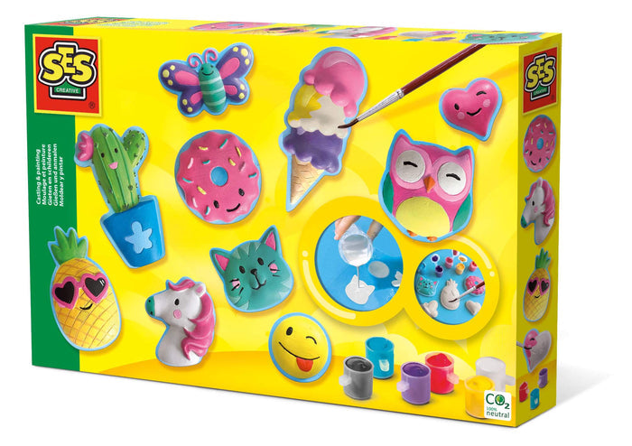Yellow craft kit box showing colorful figures like a pink owl, donut, and cat, plus paint pots and a paintbrush.