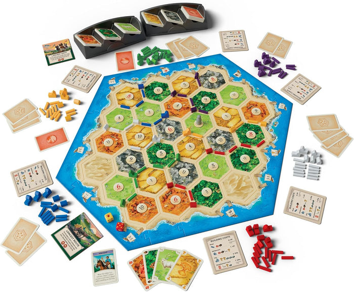 Overhead view of Catan board game with hexagonal tiles, wooden pieces in six colors, and cards spread on a blue board.