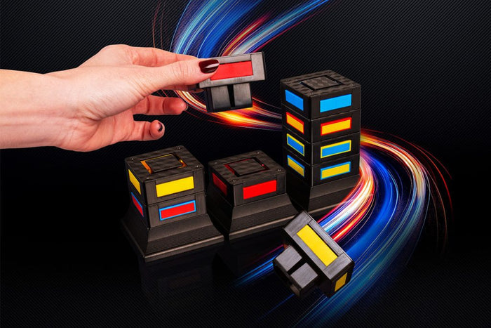 Hand stacking black plastic blocks with glowing red, blue, and yellow windows on a dark, light-streaked background.