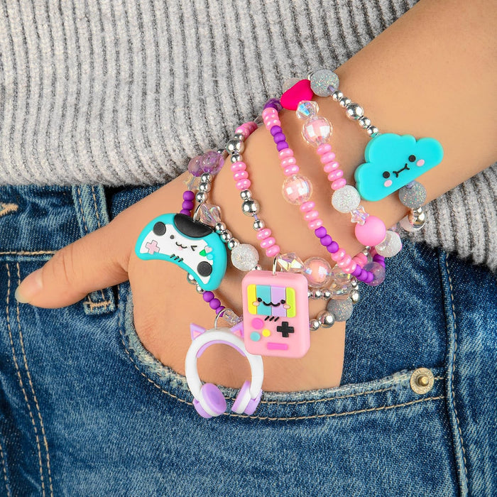 Stacked beaded bracelets with charms: a blue cloud, pink game console, video game controller, and headphones.