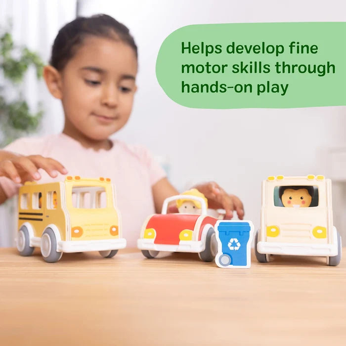 Child playing with a yellow wooden school bus, red car, and white truck featuring driver figures and a blue recycle bin.