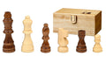 Six light and dark wood chess pieces in front of a light wood storage box with a gold latch.