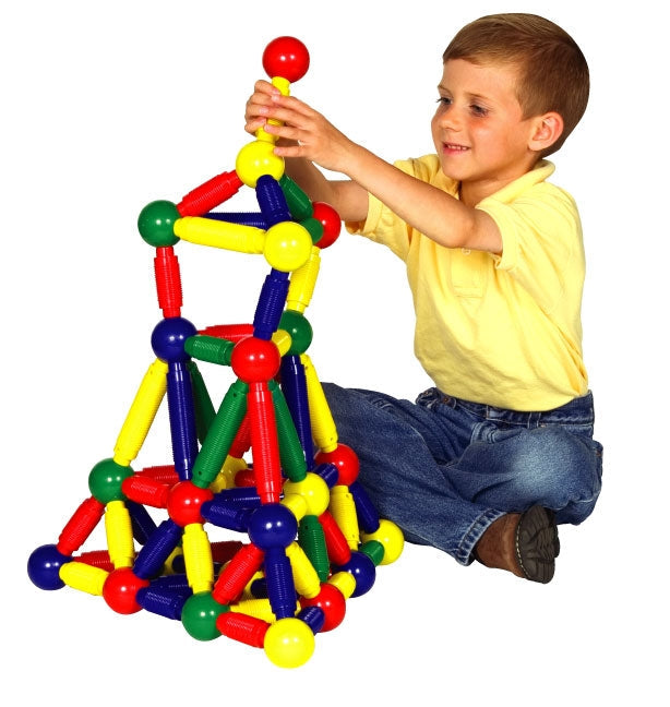 A child building a structure with large, textured primary-colored magnetic rods and spherical connectors.