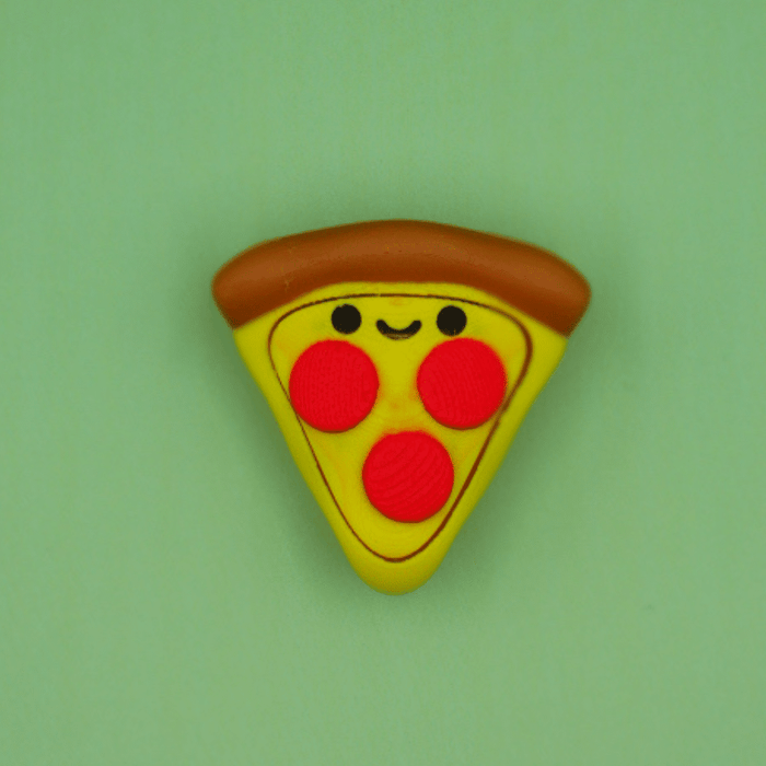 Pizza slice fidget clicker with a brown crust, yellow cheese, red pepperoni, and a happy face on a green background.
