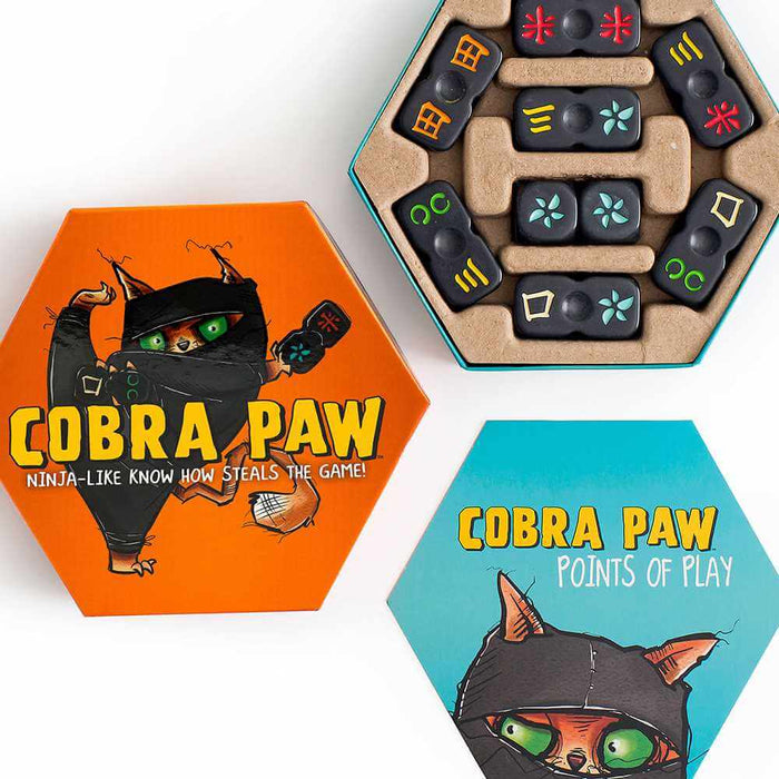 Hexagonal orange and teal Cobra Paw game boxes with ninja cat art and black game tiles featuring colorful symbols.
