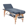 A portable massage table with navy blue upholstery, including side arm rests and a face cradle, set up for use.