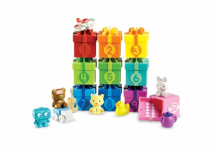 Stacked colorful toy gift boxes numbered 1 to 10 with miniature figures like a bear, cat, and duck.