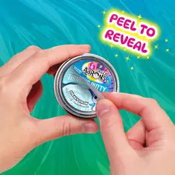 Hands peeling a sticker off a small round metal tin to reveal a hidden label against a teal swirled background.