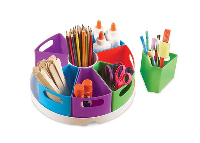 Colorful rotating organizer on a white base with wedge-shaped bins holding pencils, glue, scissors, and art supplies.
