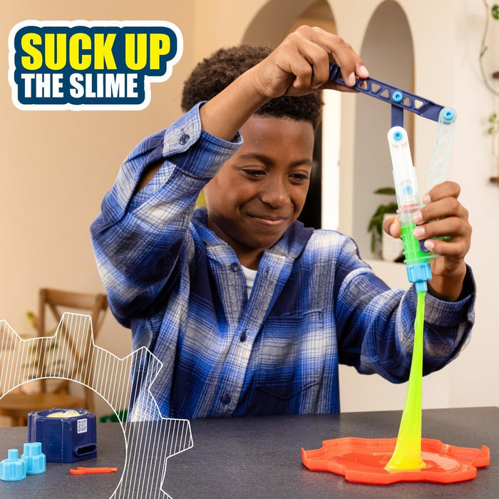 Boy using a blue mechanical tool to lift stretchy neon green slime from an orange tray.