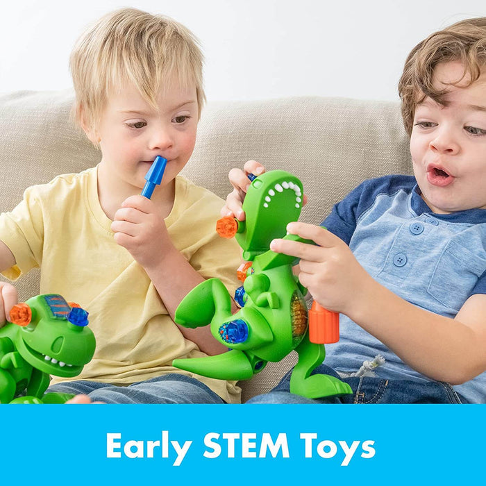 Two boys build green T-Rex toys with colorful translucent bolts and a blue handheld screwdriver tool.