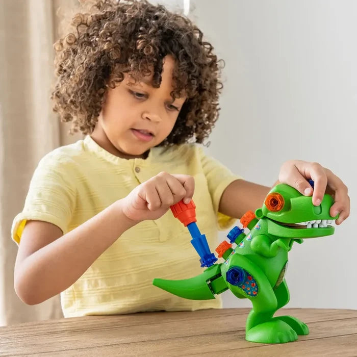 Child using a plastic screwdriver on a green T-Rex toy with colorful blue and orange bolts.