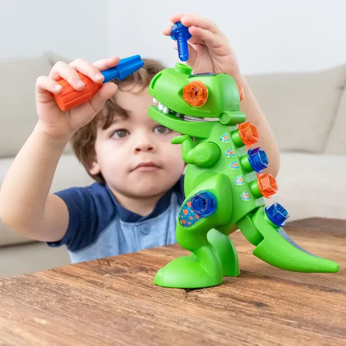 Young boy builds a green plastic T-Rex toy by inserting blue and orange screws with a toy screwdriver.