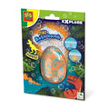 Speckled orange and blue egg bath bomb on a colorful dinosaur-themed card with tropical leaves and bubbles.