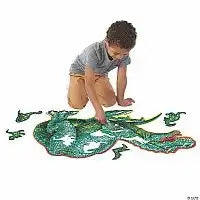 A child assembling a large, green dinosaur-shaped floor puzzle with scattered pieces on a plain white background.