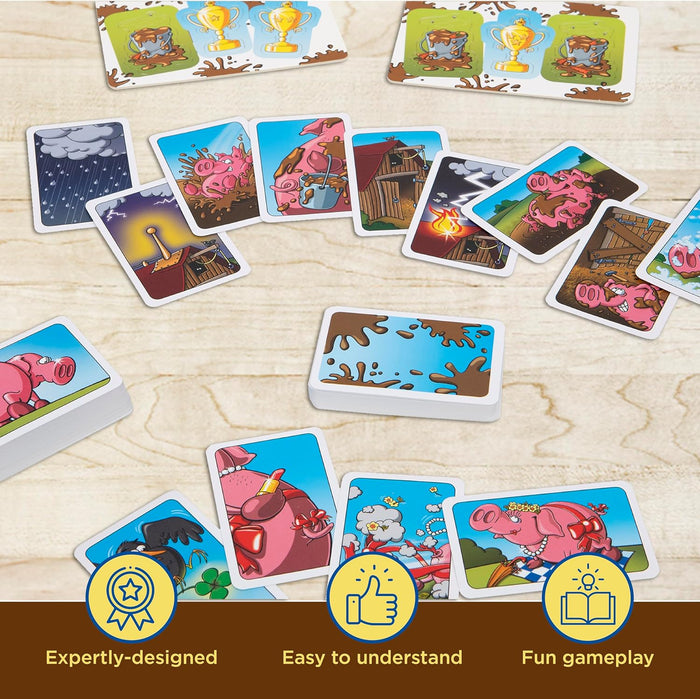 Colorful card game featuring pink pigs, mud splats, and farm scenes scattered on a light wooden surface.