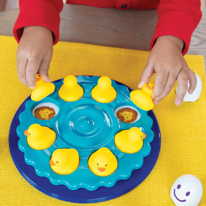 Child lifts yellow rubber ducks from a teal spinning base to reveal hidden matching lion icons.