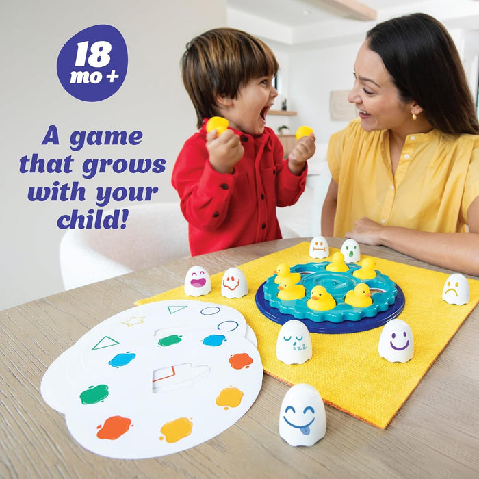 Toddler playing with yellow ducks on a blue base, white pieces with faces, and colorful shape and color boards.