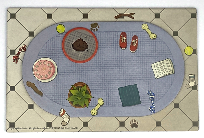 Top-down game tile featuring a blue rug on a tiled floor with dog toys, a pink cake, and a pile of dog poop.
