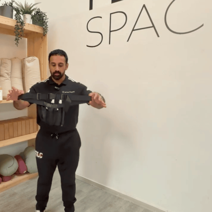 A male therapist presenting a black Double Massage Oil Holster from Massage Warehouse, supplying professional clinic equipment across the UK and Ireland; isolates the stain-resistant, heavy-duty woven nylon fabric and its deep twin sleeve pockets tailored to securely hold two standard 250ml pump bottles for active mobile therapists in Glasgow.