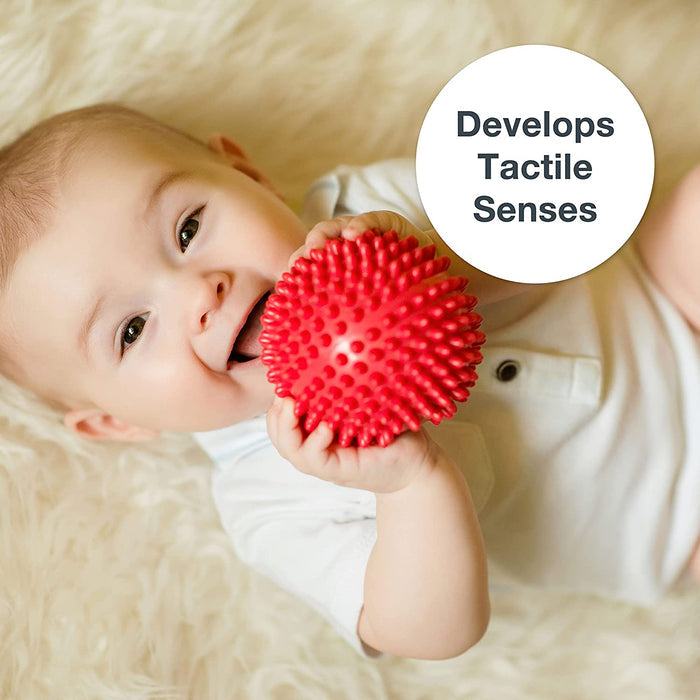 Baby holding a textured red sensory ball near their mouth. Text reads: Develops Tactile Senses.