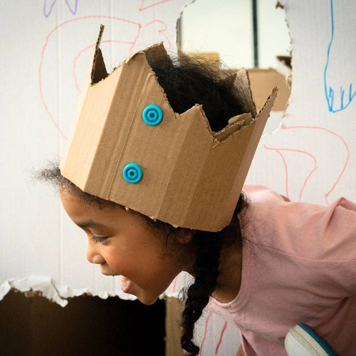 Young girl wearing a jagged cardboard crown fastened with two bright blue plastic Makedo connector pieces.