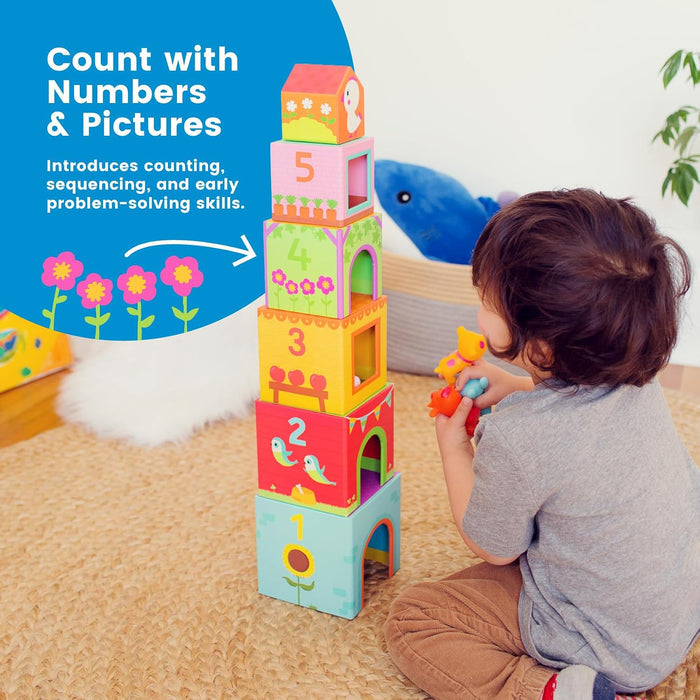 Child plays with colorful stacked nesting blocks numbered 1-5 featuring nature illustrations and a small toy house.