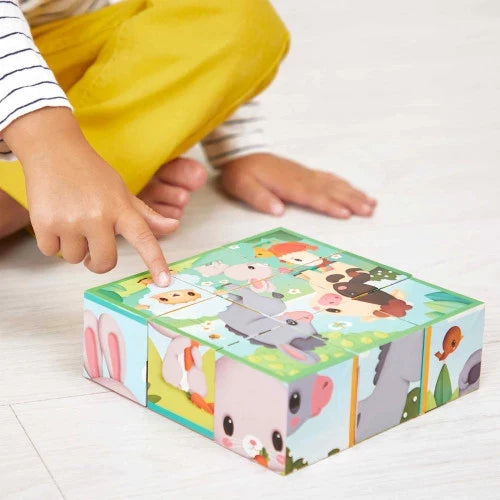 Child pointing at colorful cardboard cube blocks featuring illustrated farm animals like a rabbit, sheep, and donkey.