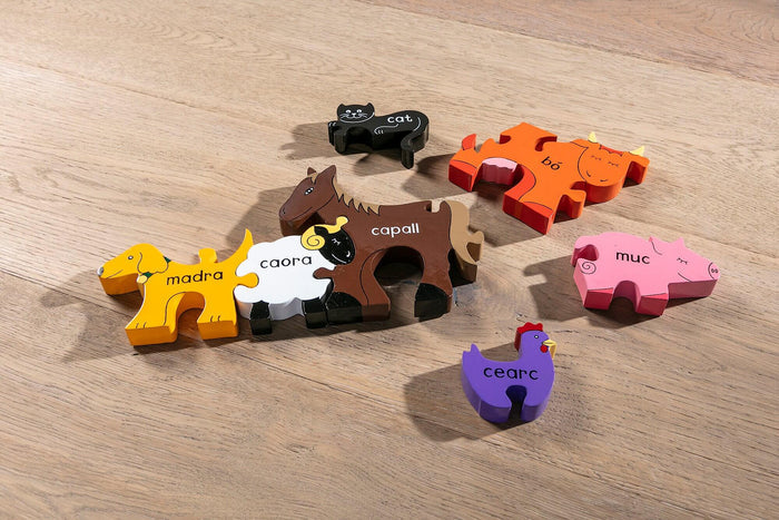 Brightly colored wooden puzzle pieces shaped like a yellow dog, brown horse, and pink pig with Irish names.