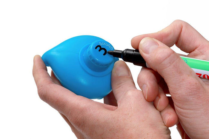 Close-up of hands writing the number 3 with a black marker on the base of a blue plastic toy duck.