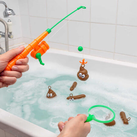 Orange toy rod and green net catching brown poop-shaped floaties with googly eyes in a soapy bathtub.