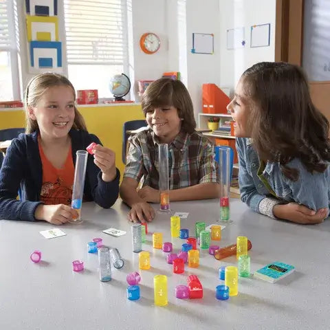 Three children playing a math game with clear tubes and colorful cylinders labeled with fractions on a table.