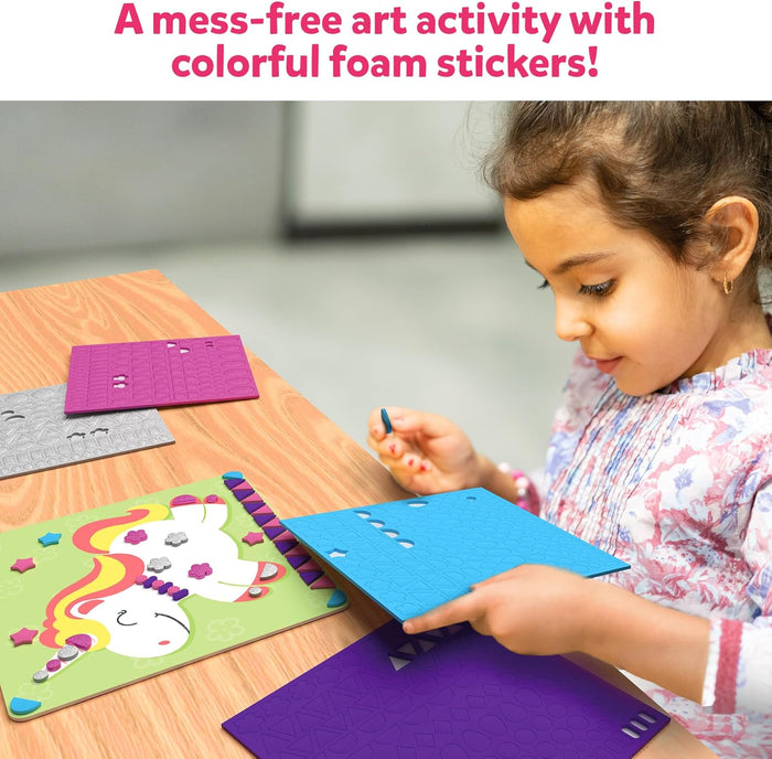 Young girl decorating a unicorn art board with colorful foam stickers from several sheets on a wooden table.
