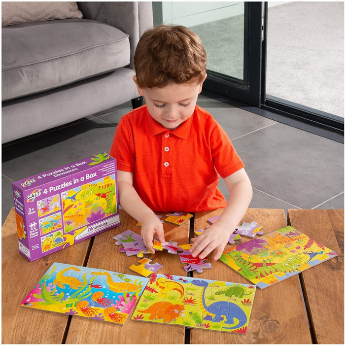 A child assembles colorful Galt dinosaur puzzles from a purple box on a wooden table.